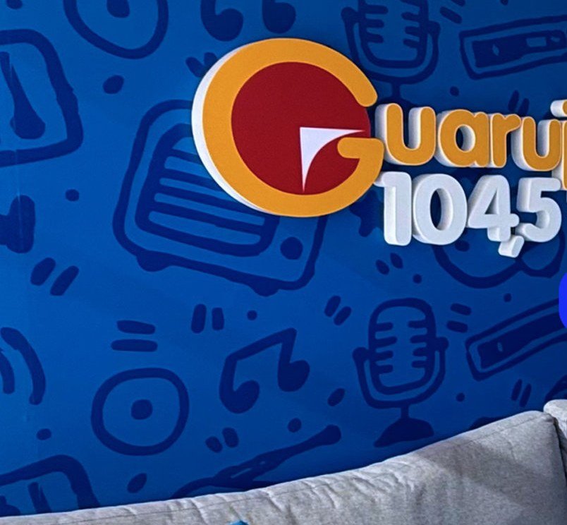 Detalhe do logotipo Guarujá 104,5 FM aplicado em parede com padrão gráfico
